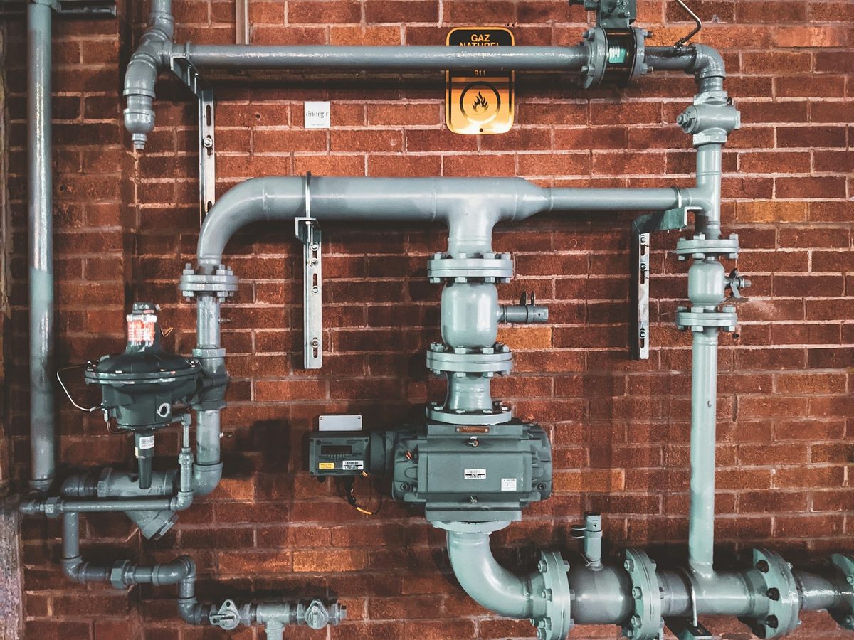 Industrial pipework and valves on a brick plant wall